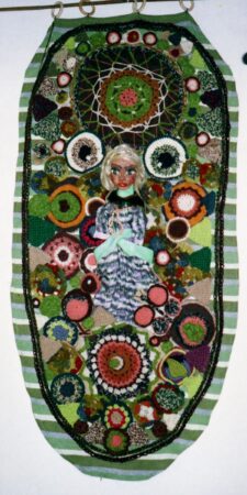 Groen wandkleedje met bloemmotieven en een poppengezicht